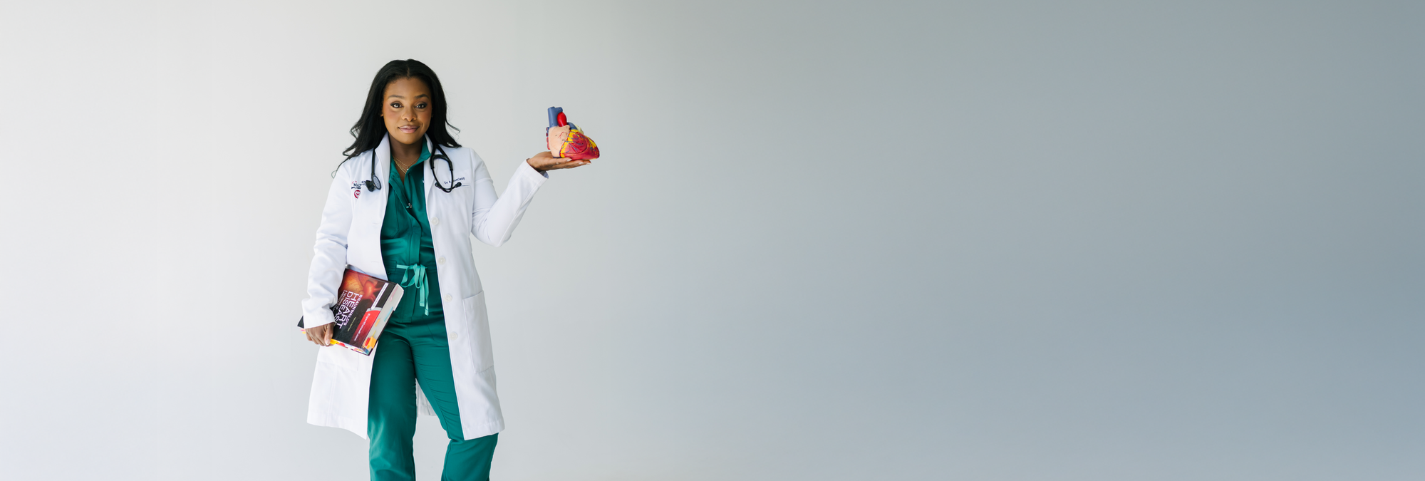Dr Bastiany is Suna's Ambassador. Banner showing Dr. Alex Bastiany holding a heart model and holding a book