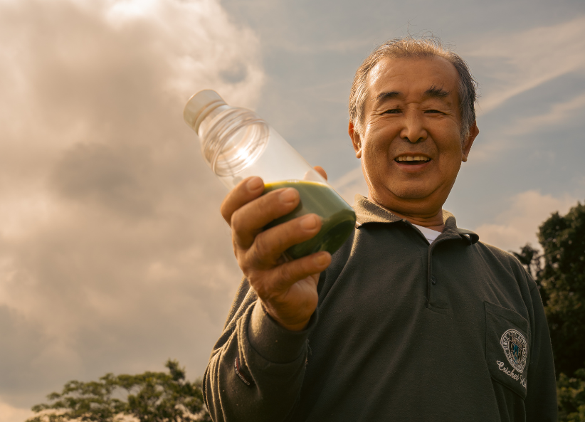 a Japanese tea farmer holding a bottle of Suna Protein Tea Latte